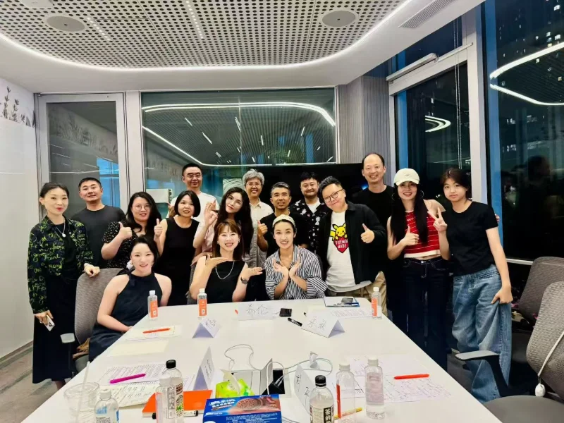 小组成员在会议桌旁合影，桌上保留讨论资料